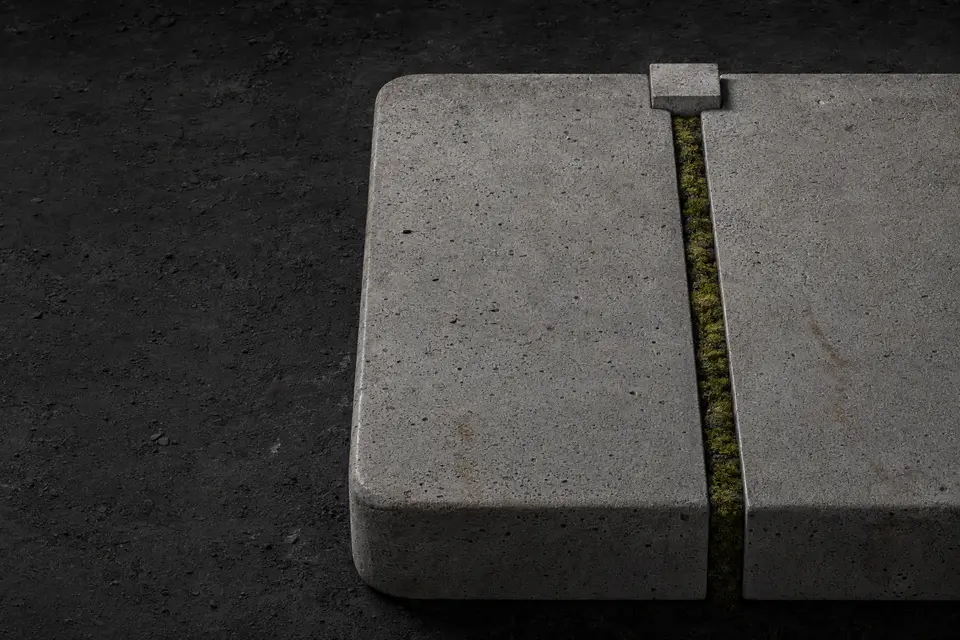 A monolithic concrete capsule divided by one narrow seam of living moss